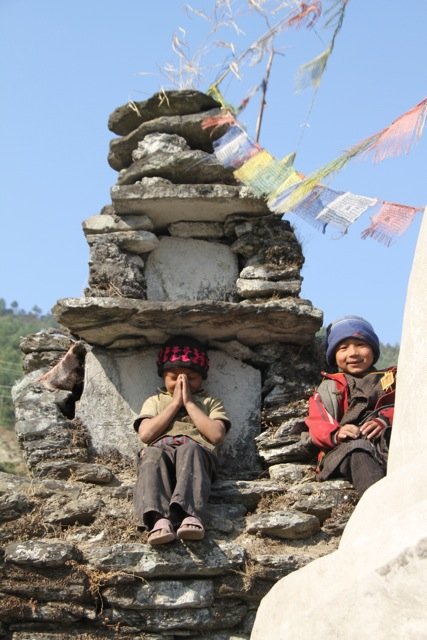 Niños junto a un stupa con banderas de oración en un pueblo de Nepal